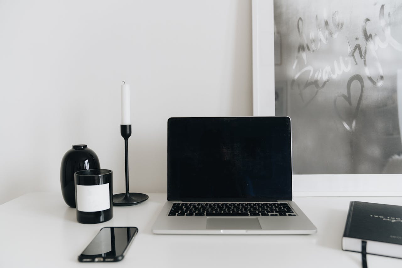 A clean and modern home office desk setup with a laptop, smartphone, and decor elements.